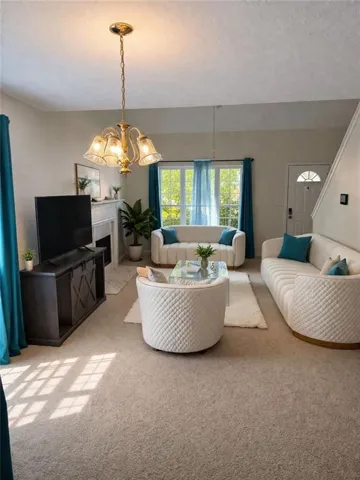 Living area with light carpet, hanging lights, a fireplace with flush hearth, and a textured ceiling