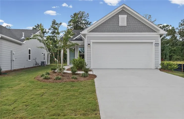 Light gray siding exterior with a contrasting gray shingle gable, attached two-car garage, concrete driveway, and landscaped front yard