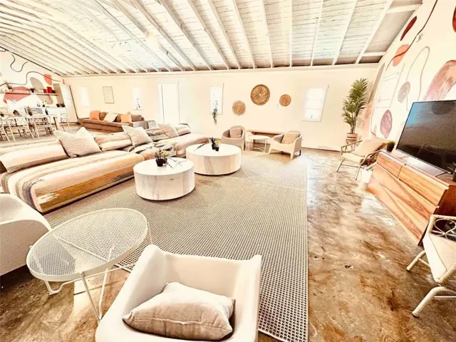 Living room featuring wood ceiling, concrete flooring, and vaulted ceiling with beams