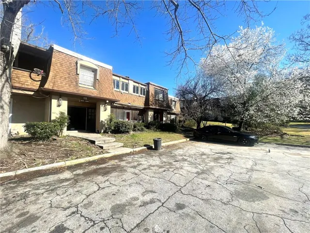 View of front of home featuring mansard roof, a shingled roof, a residential view, and stucco siding