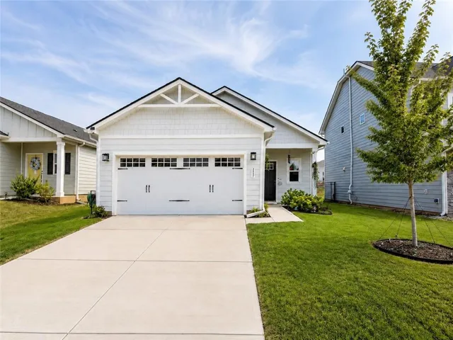 Exterior featuring light-colored siding, a prominent attached garage with window inserts, a gabled roofline, and a concrete driveway