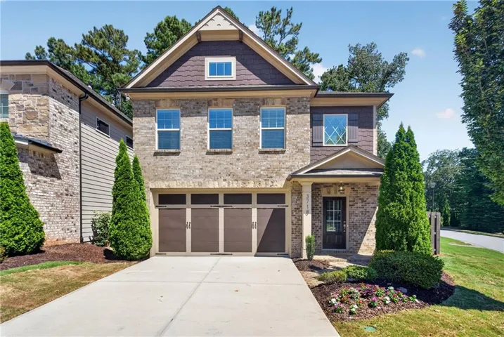 Brick and siding exterior with a two-car garage, covered entry, and established landscaping