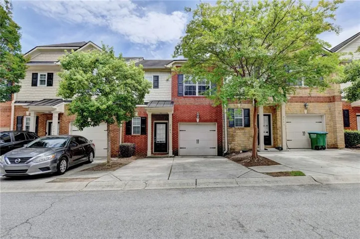 Multi-story townhouse featuring a brick and siding exterior with an attached garage