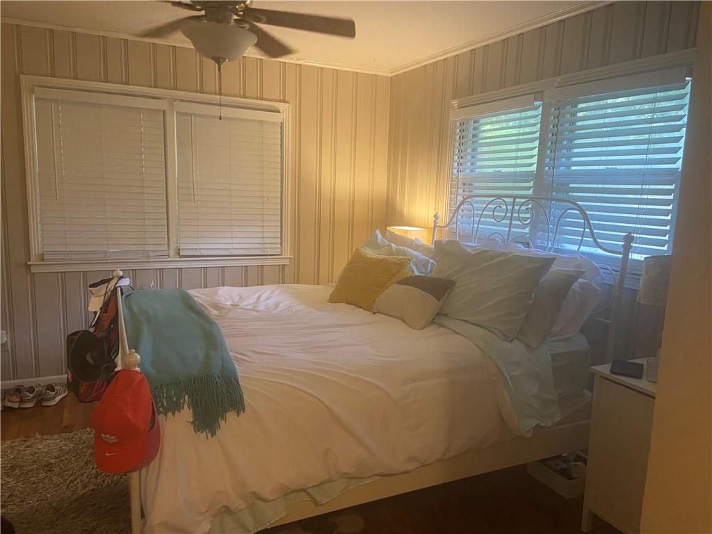Bedroom featuring wood-type flooring, ornamental molding, and ceiling fan