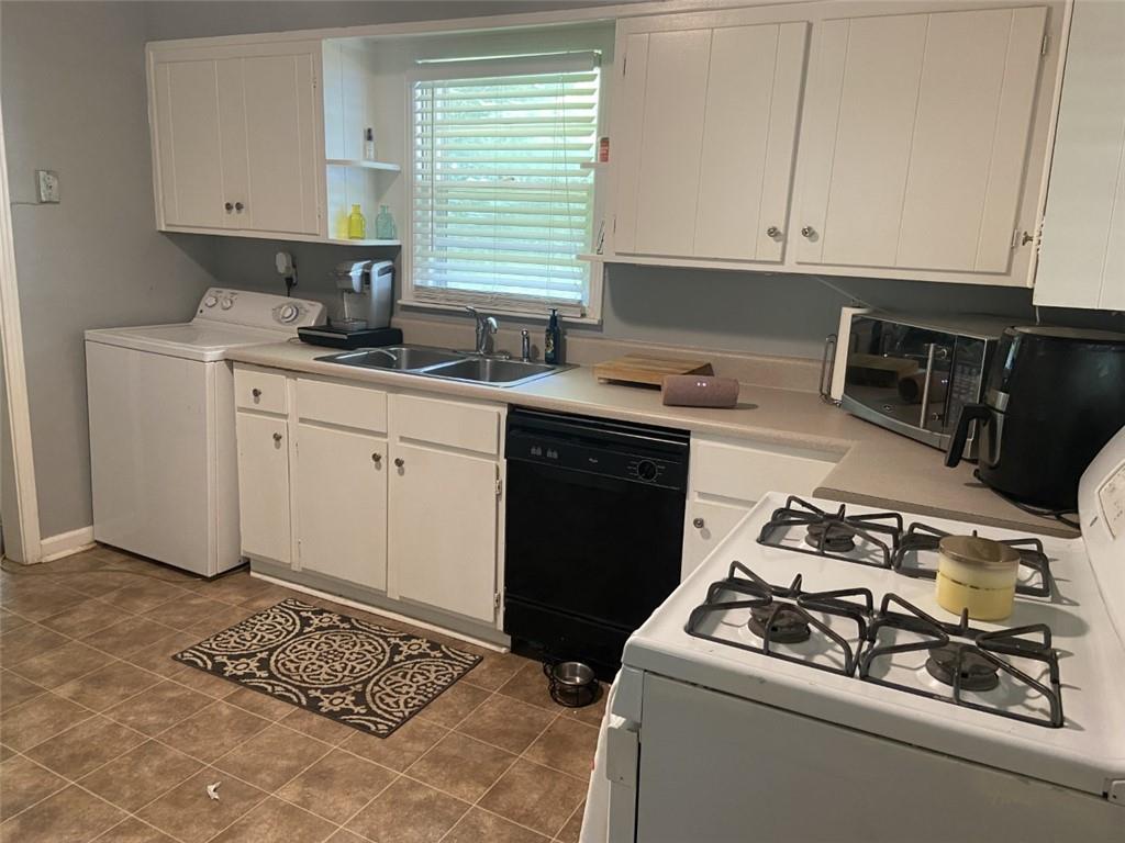 Kitchen with sink, dishwasher, washer / clothes dryer, and white cabinetry