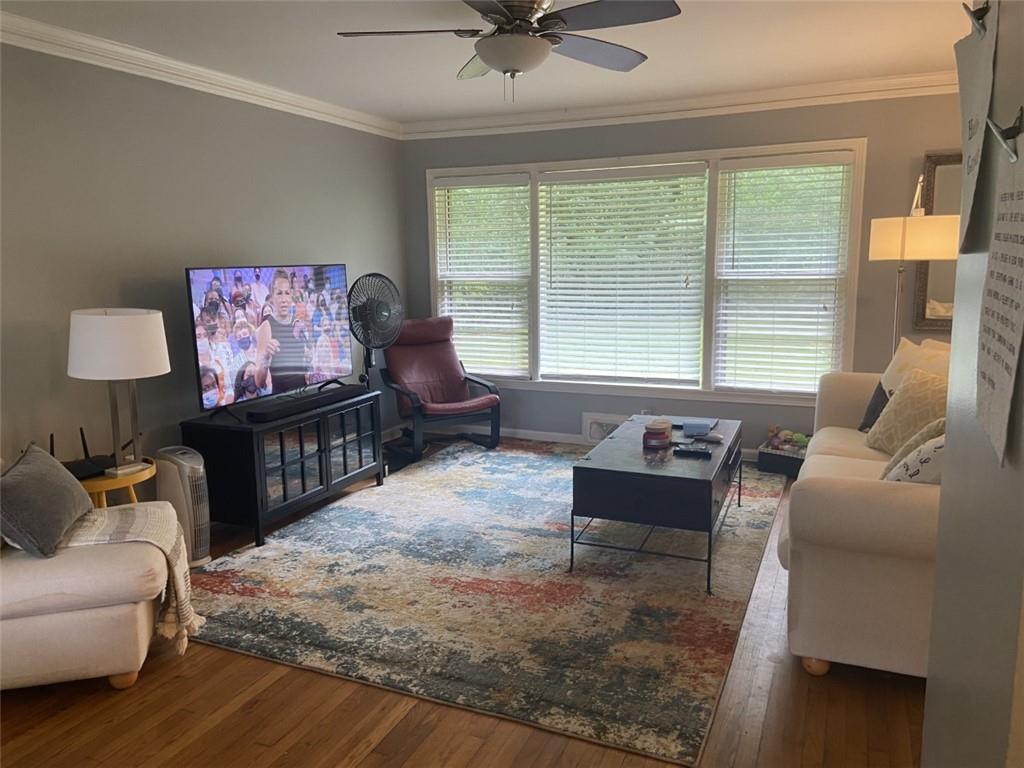 Living room featuring ornamental molding, dark wood-type flooring, and ceiling fan