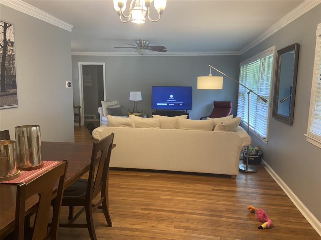 Living room with crown molding, ceiling fan with notable chandelier, and hardwood / wood-style floors