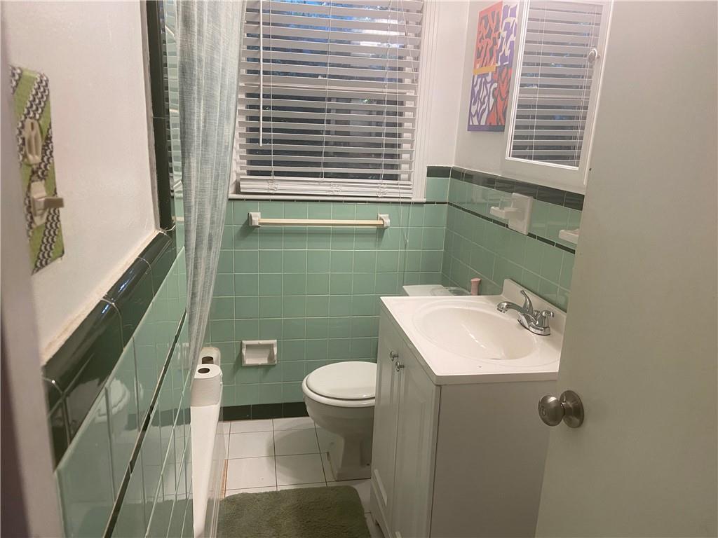 Bathroom featuring tile walls, toilet, tile flooring, and oversized vanity
