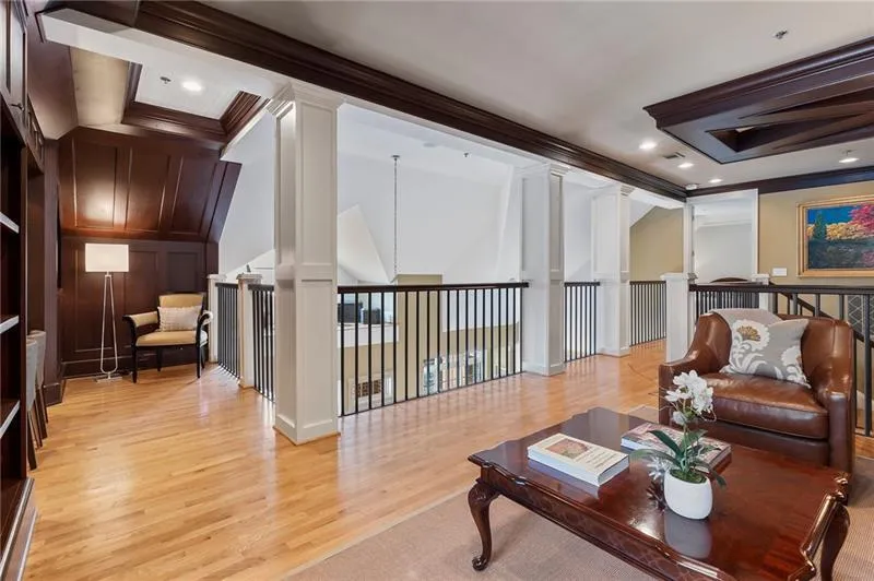 Living area with ornamental molding, light wood-style flooring, a decorative wall, and ornate columns