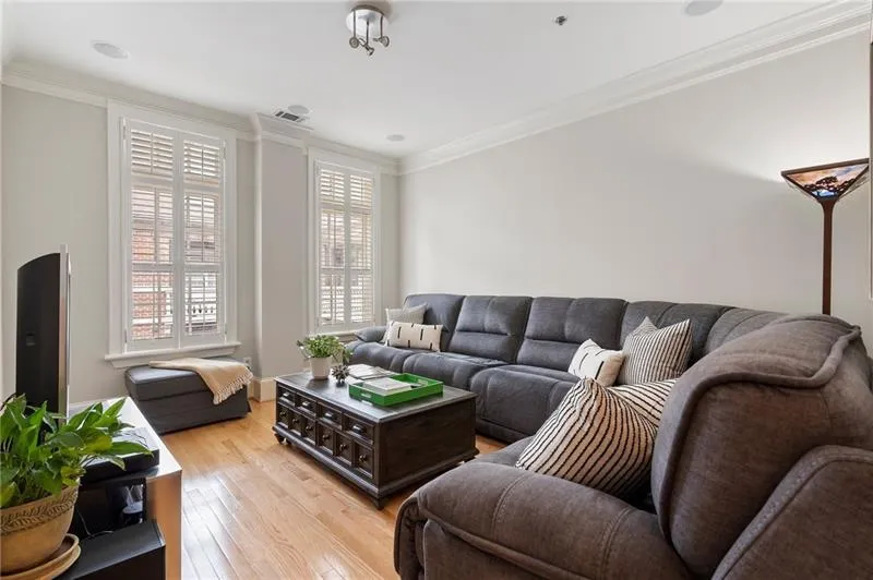 Living room with visible vents, light wood-type flooring, and crown molding