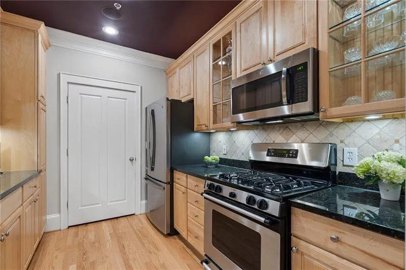 Kitchen with appliances with stainless steel finishes, light wood-type flooring, crown molding, and backsplash