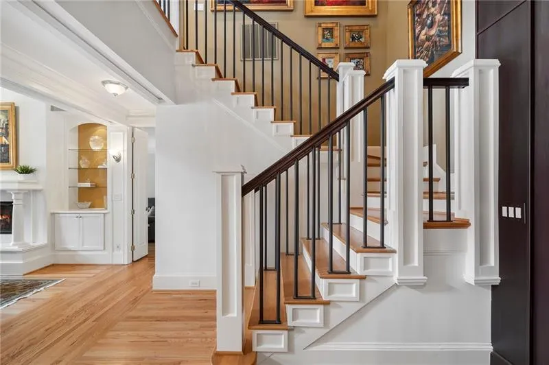 Stairs featuring a high end fireplace, built in features, wood finished floors, and baseboards
