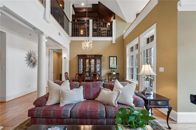 Living area featuring an inviting chandelier, wood finished floors, baseboards, and a high ceiling