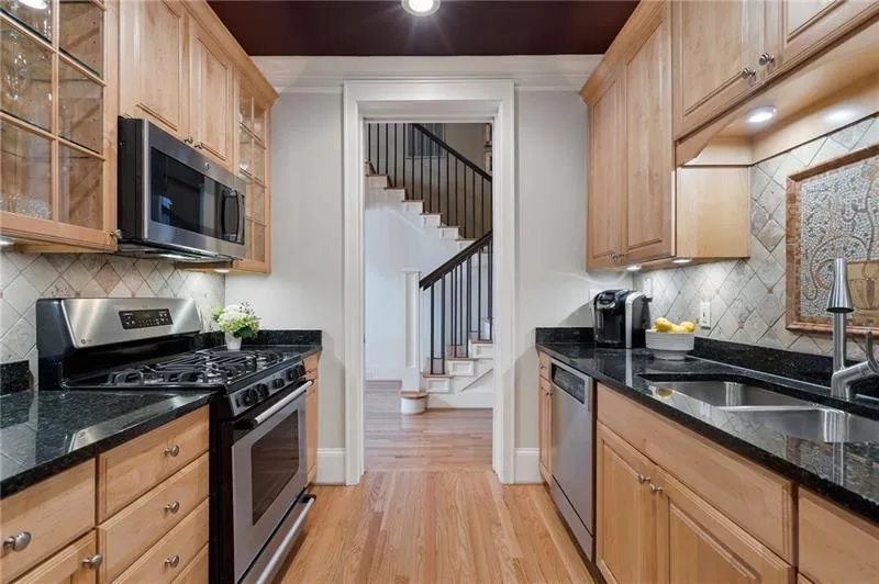 Kitchen featuring appliances with stainless steel finishes, backsplash, light wood finished floors, a sink, and baseboards