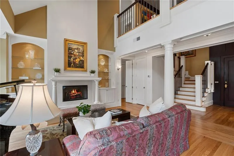 Living room with built in shelves, a high ceiling, visible vents, and wood finished floors