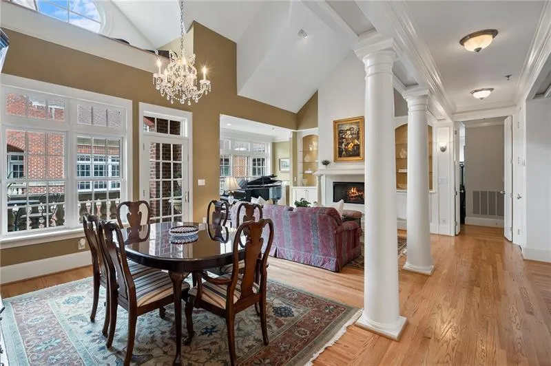 Dining space featuring high vaulted ceiling, built in features, light wood-type flooring, a lit fireplace, and ornate columns