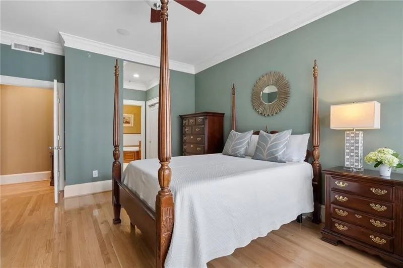 Bedroom with light wood finished floors, ensuite bath, crown molding, visible vents, and baseboards