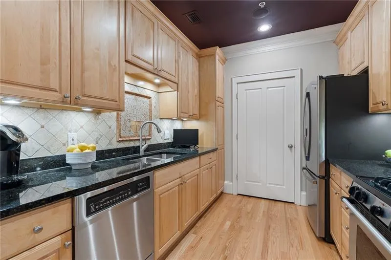 Kitchen featuring a sink, stainless steel appliances, light brown cabinetry, visible vents, and ornamental molding