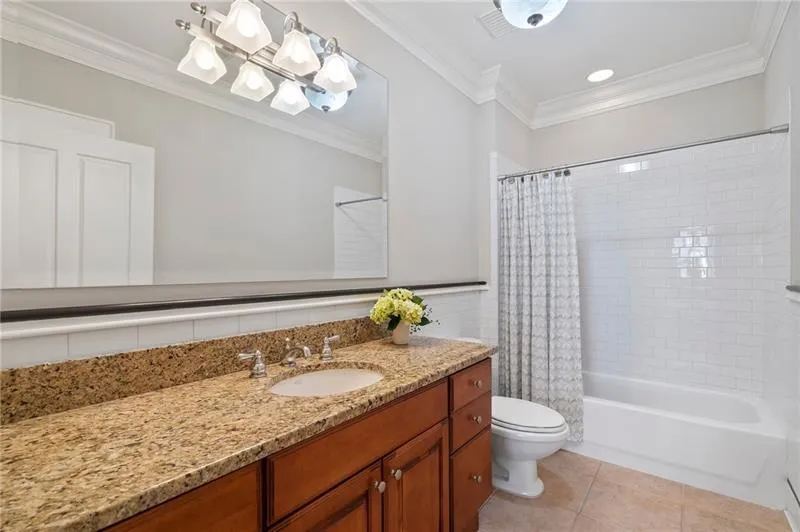 Bathroom with tile patterned floors, shower / bath combination with curtain, toilet, vanity, and crown molding
