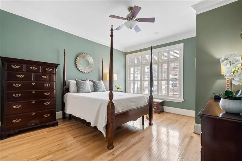 Bedroom with light wood-style floors, a ceiling fan, ornamental molding, and baseboards