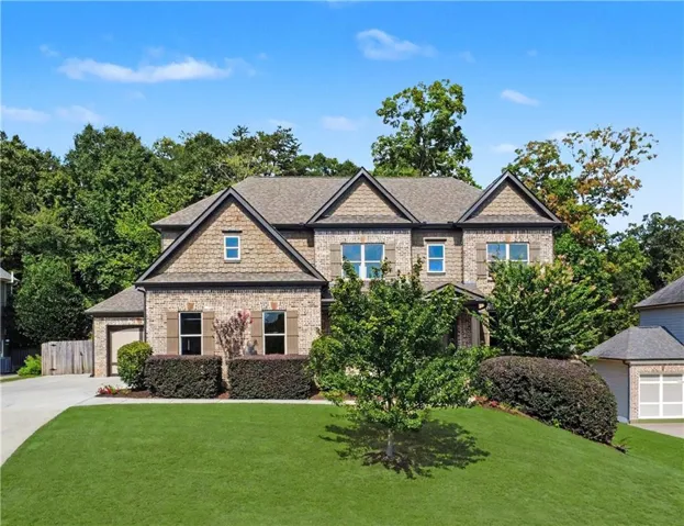 Two-story brick and shake exterior with a multi-gabled roofline, multiple windows, and a paved driveway