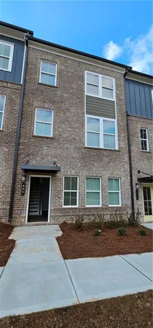 Modern brick townhome featuring a clean facade with multi-pane windows, a recessed entry with black door and sidelights, and a newly poured concrete walkway