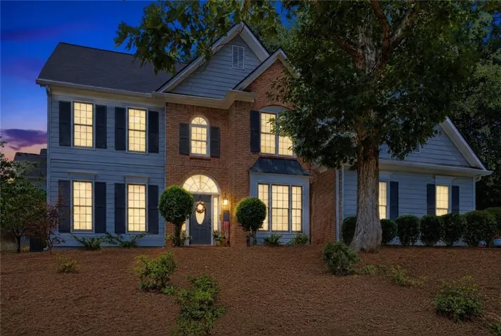 Two-story residence featuring brick and siding facade, arched entryway, bay window, and dark shutters