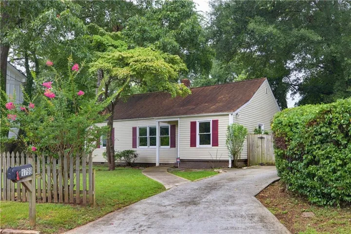 Ranch-style residence featuring light-colored siding, a brown shingle roof, and contrasting red window shutters