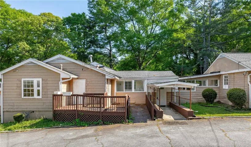 Exterior featuring siding, a wooden deck with railing, and a covered entrance with a ramp