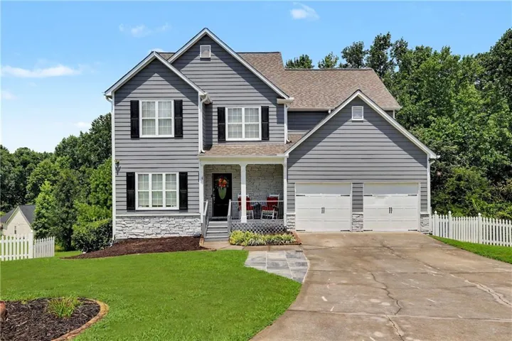 Two-story residence featuring gray siding, a stone veneer foundation, and a covered front porch
