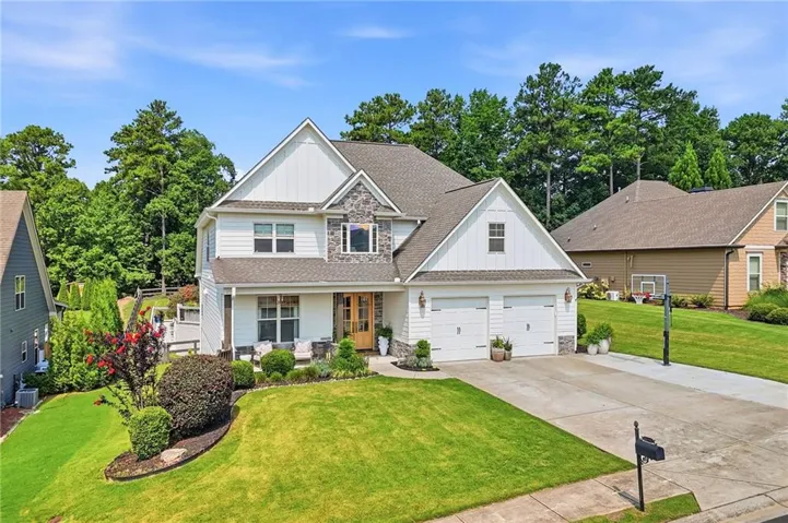 Two-story residence featuring a two-car garage, stone accents, and a covered porch