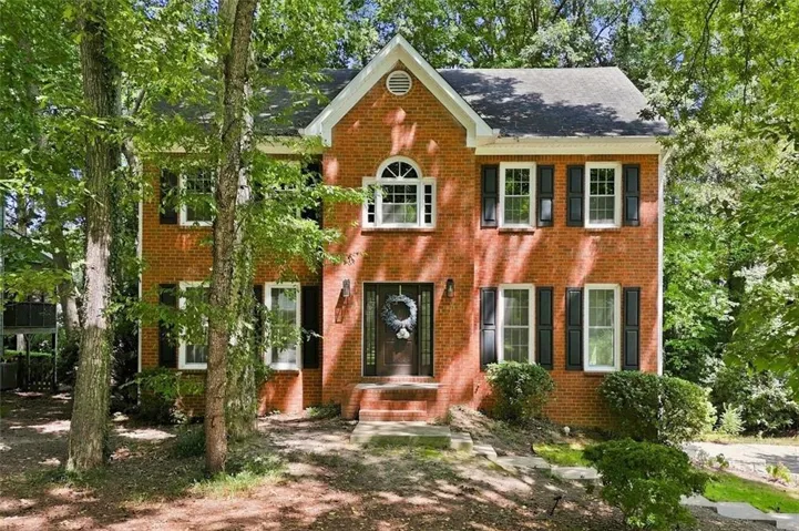 Brick exterior with white window trim, black shutters, prominent front entry, and a gabled roofline