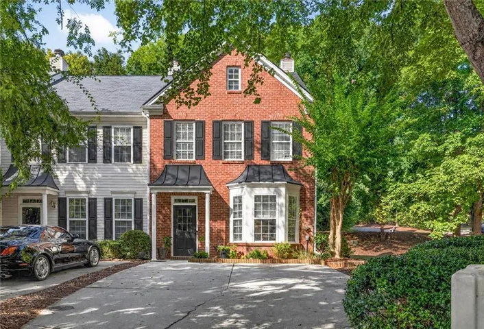 Brick exterior featuring a bay window, black shutters, and a covered entry
