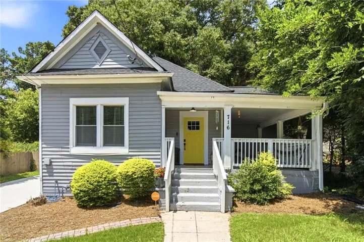 Charming exterior with light gray siding and a bright yellow front door