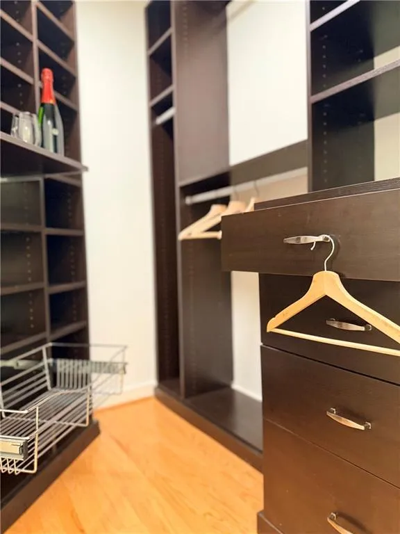 Spacious closet featuring light wood-style flooring Spacious closet featuring light wood-style flooring