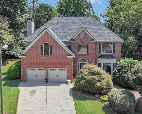 Brick exterior with a gabled roofline, featuring a two-car garage, bay window, and arched entryway
