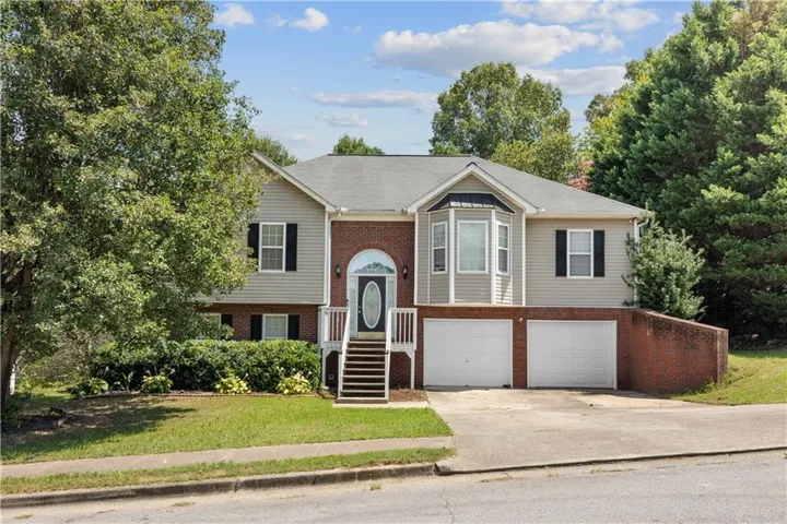 Split-level residence featuring a brick and siding exterior, bay window, two-car garage, and established landscaping