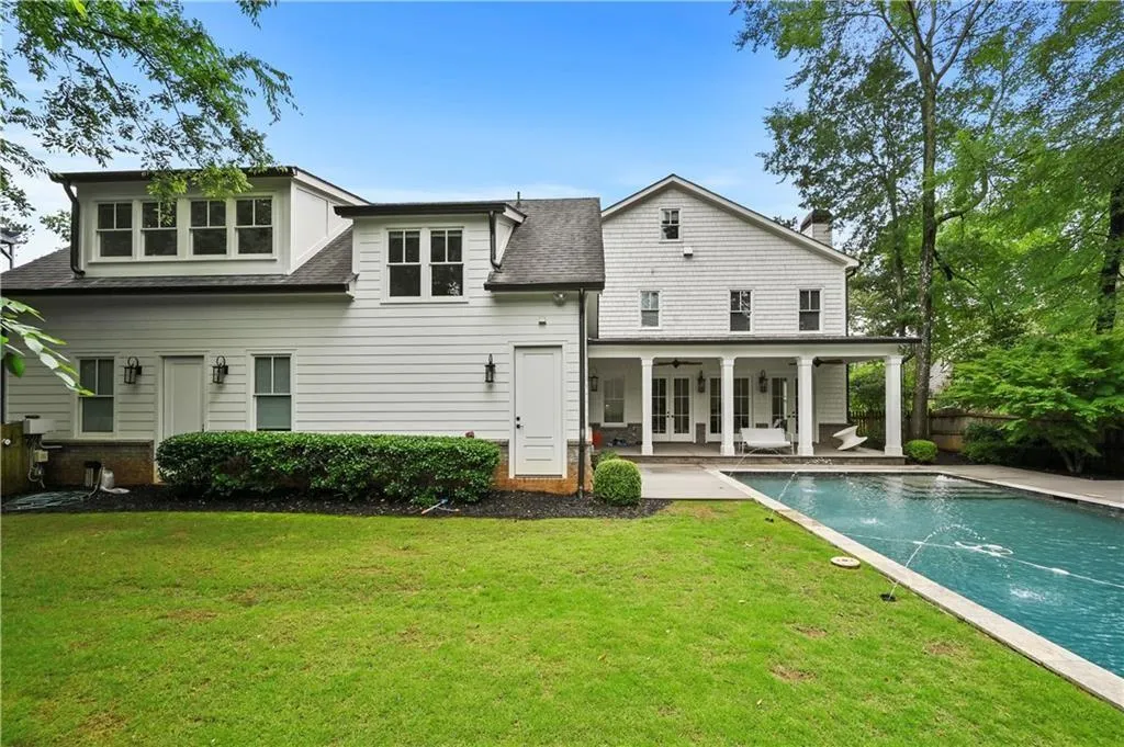 Back of property with a shingled roof, a patio, an outdoor pool, french doors, and a ceiling fan