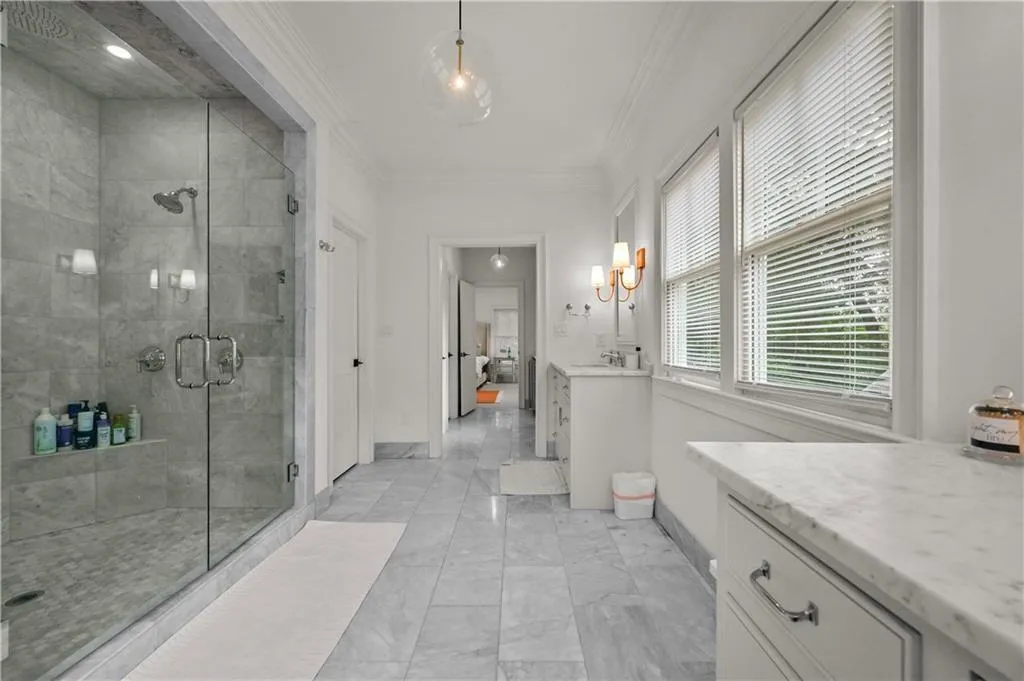 Bathroom with vanity, crown molding, a stall shower, marble look tiles, and a chandelier