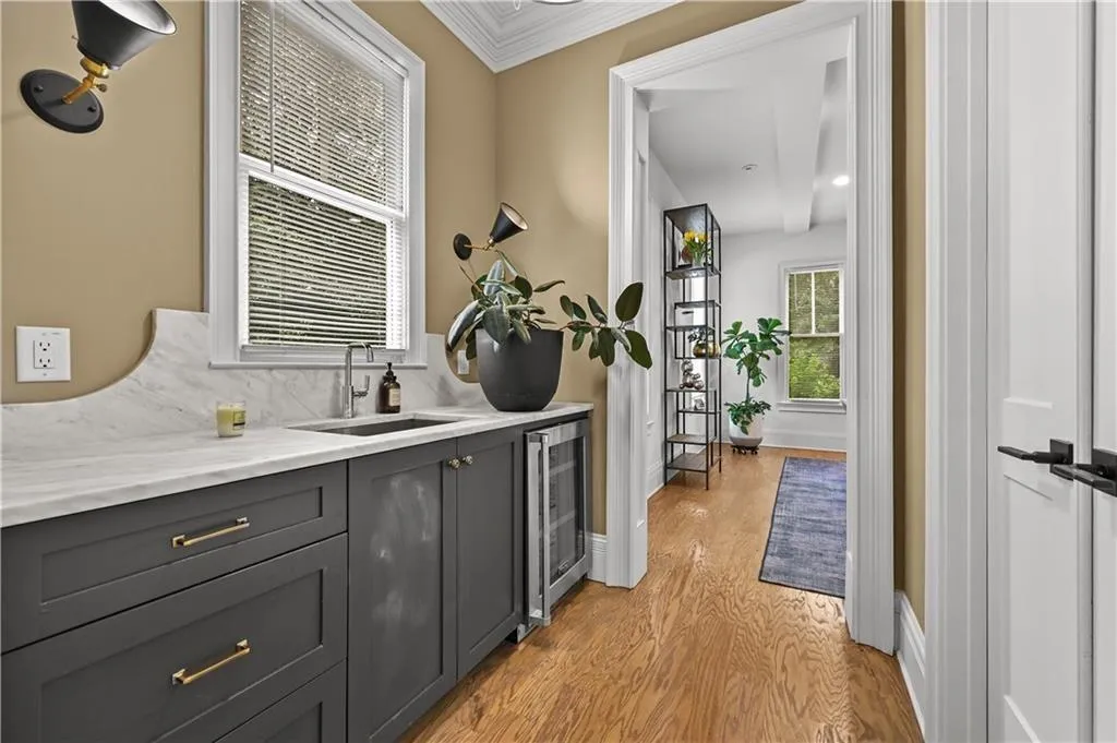 Bar area with crown molding, light wood-type flooring, and wine cooler