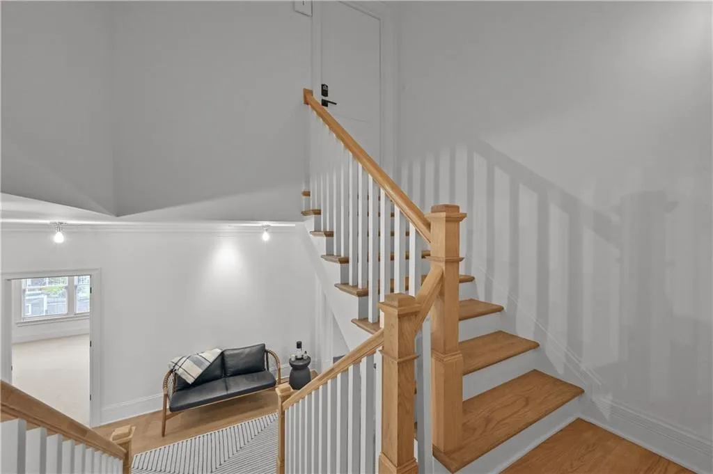 Stairs with wood finished floors and crown molding