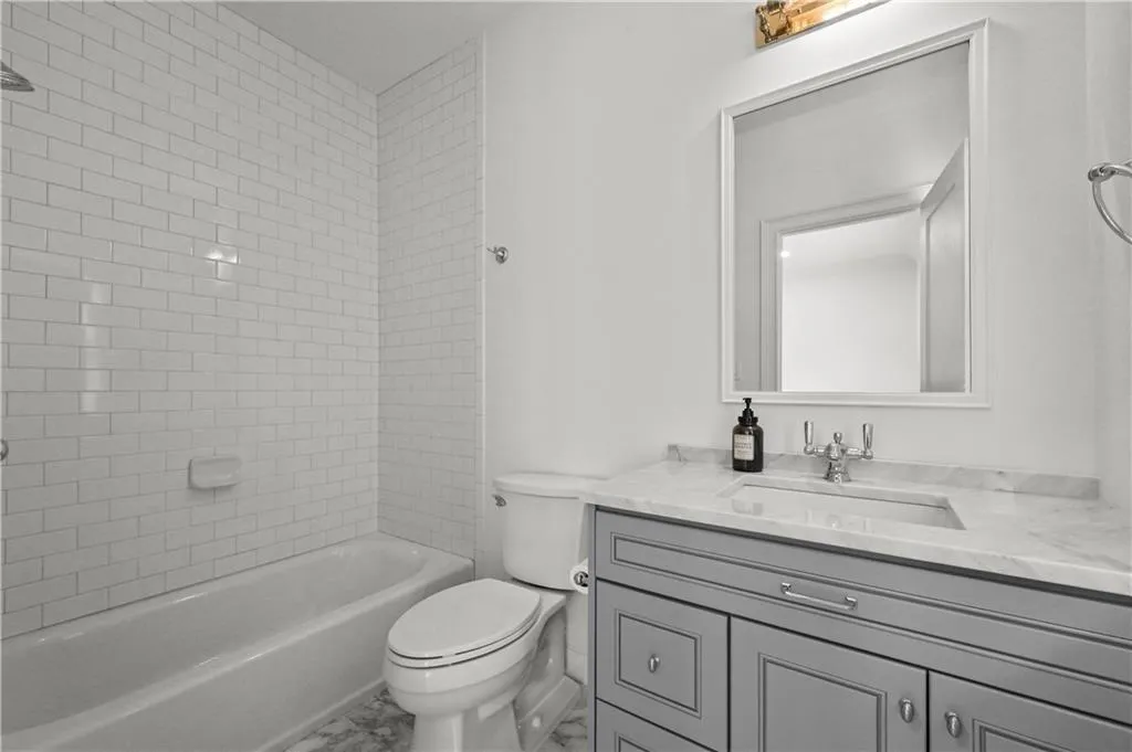 Bathroom with vanity, marble finish flooring, and bathing tub / shower combination