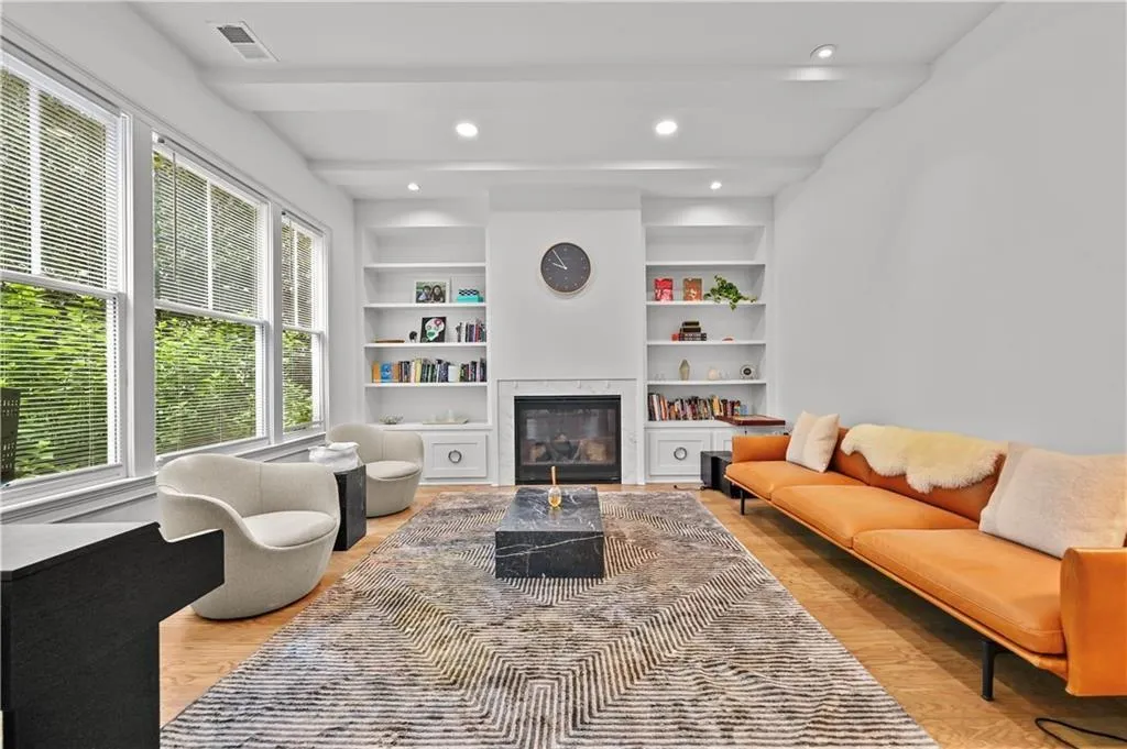 Living room featuring built in features, recessed lighting, a glass covered fireplace, light wood-style floors, and beamed ceiling