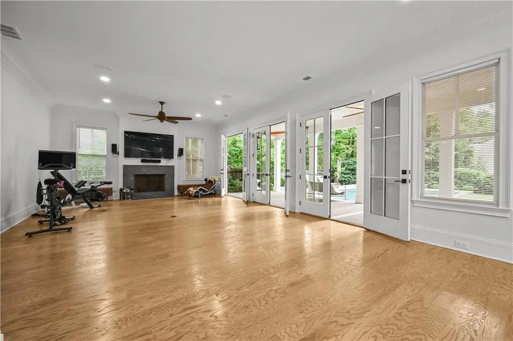 Exercise room featuring crown molding, french doors, a fireplace, wood finished floors, and recessed lighting