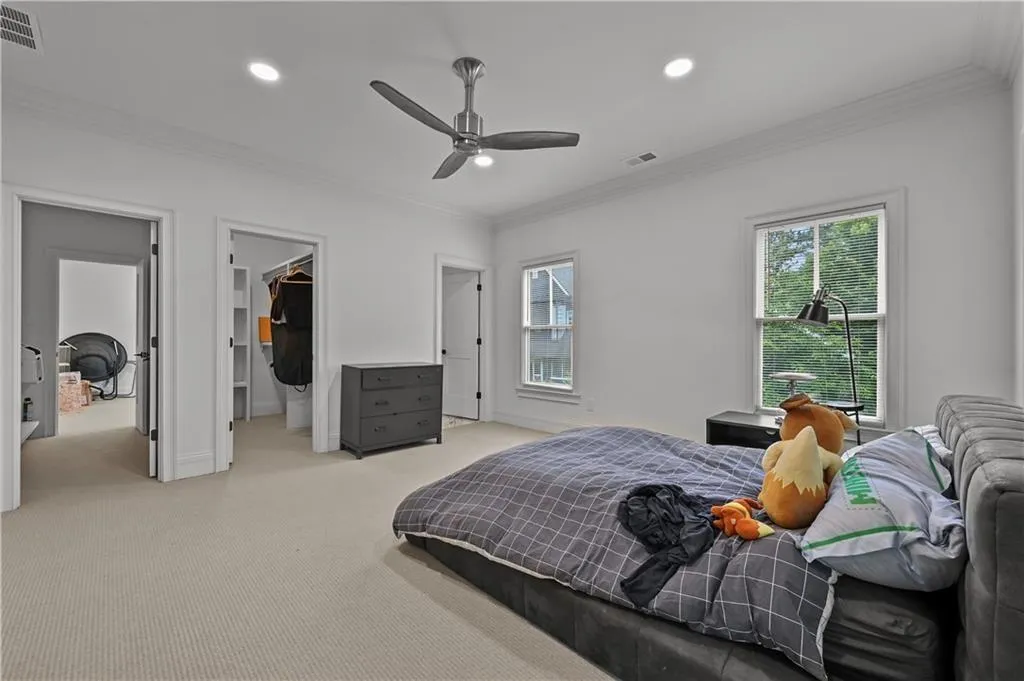 Bedroom featuring multiple windows, ornamental molding, recessed lighting, a spacious closet, and light colored carpet