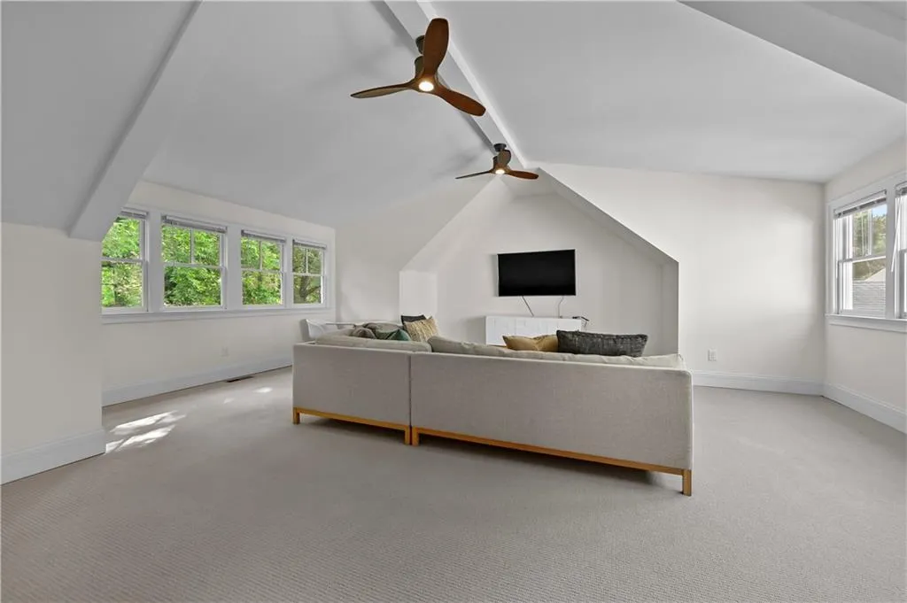 Living area with light colored carpet and a ceiling fan