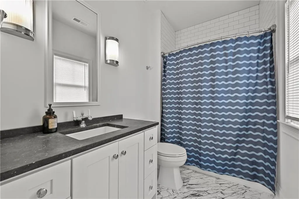 Bathroom with vanity, marble finish floors, and a shower with shower curtain