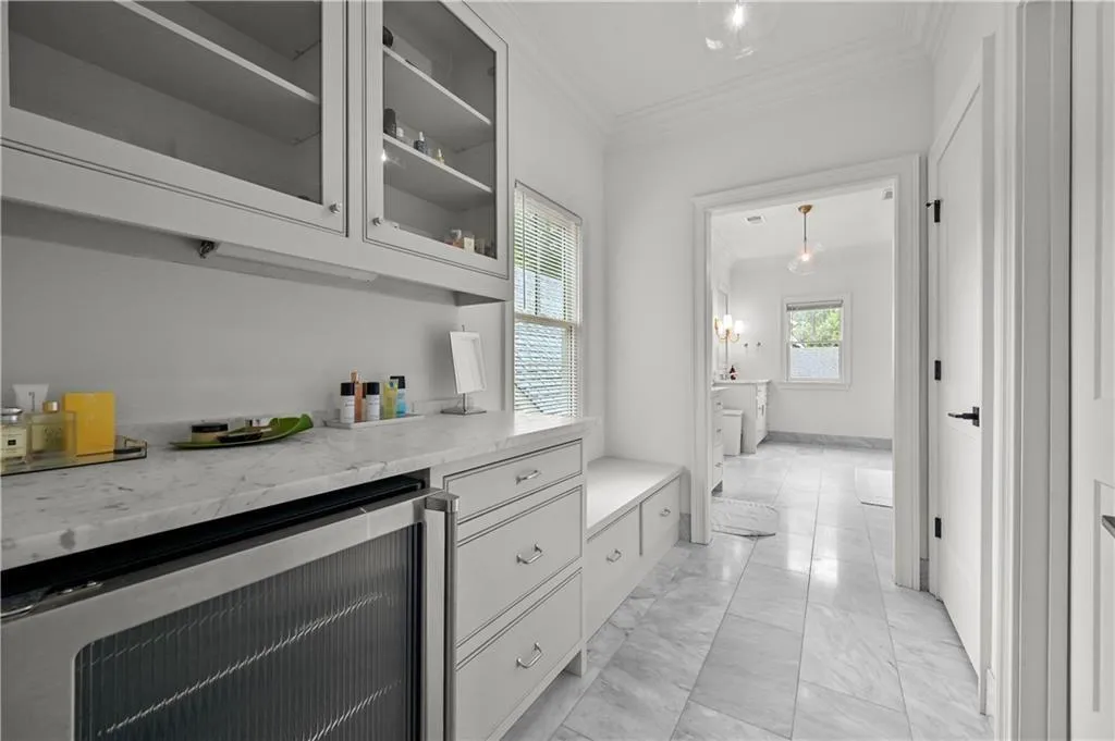 Bar featuring wine cooler, crown molding, and light marble finish flooring