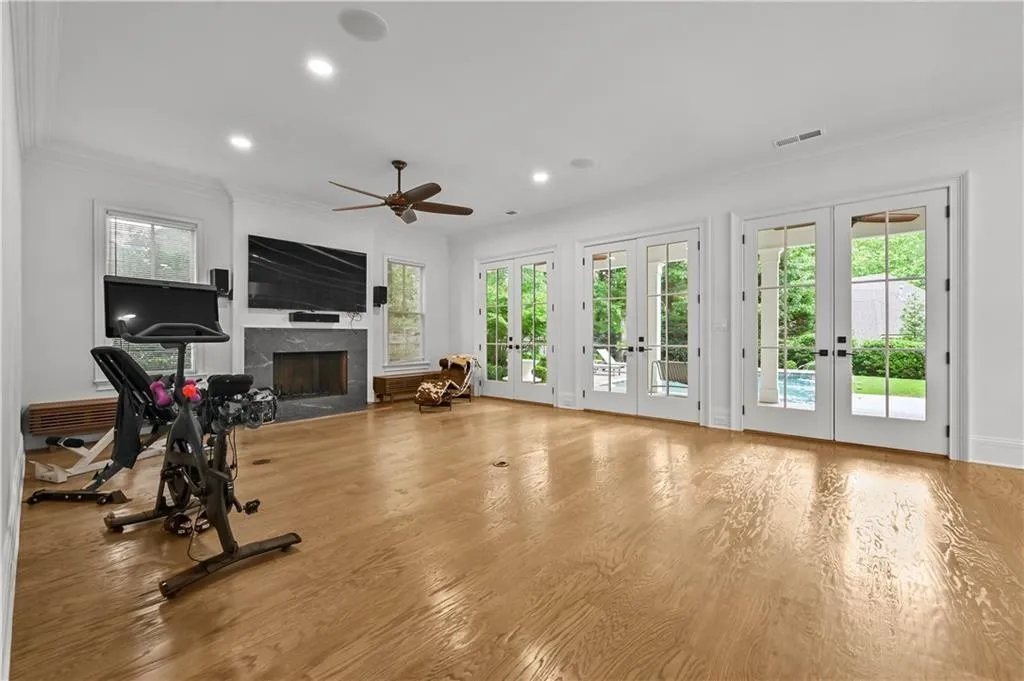 Exercise room with french doors, a fireplace, crown molding, wood finished floors, and recessed lighting