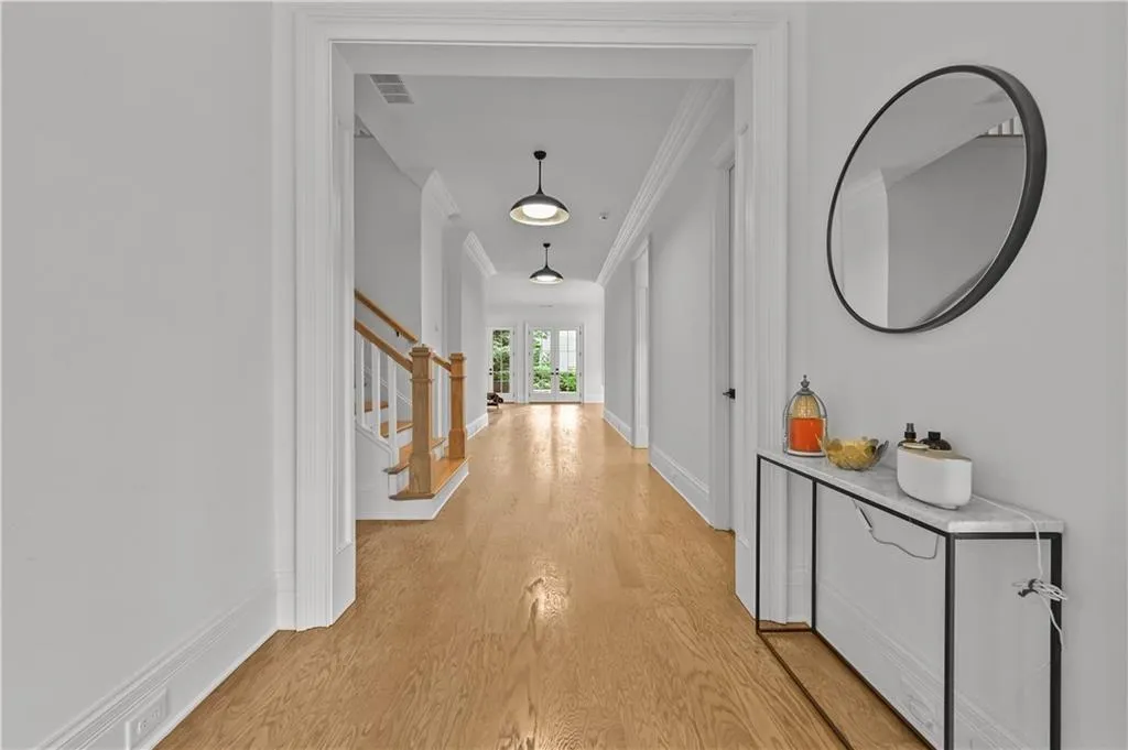 Corridor featuring ornamental molding, light wood finished floors, and stairs